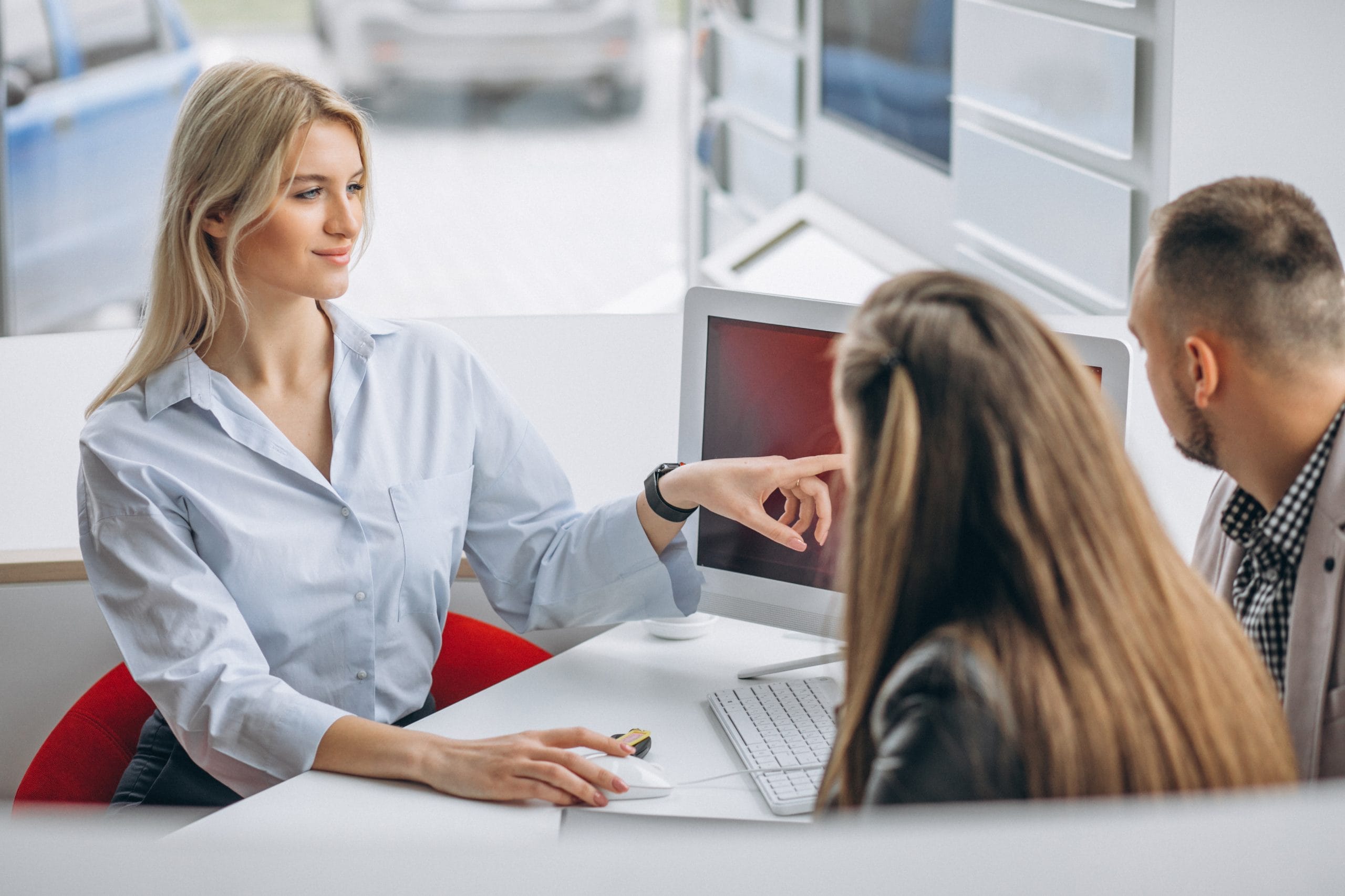 A clinician talking with two patients across a desk in a consulting room